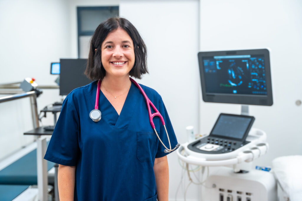 Cardiologist in medical scrubs, smiling.