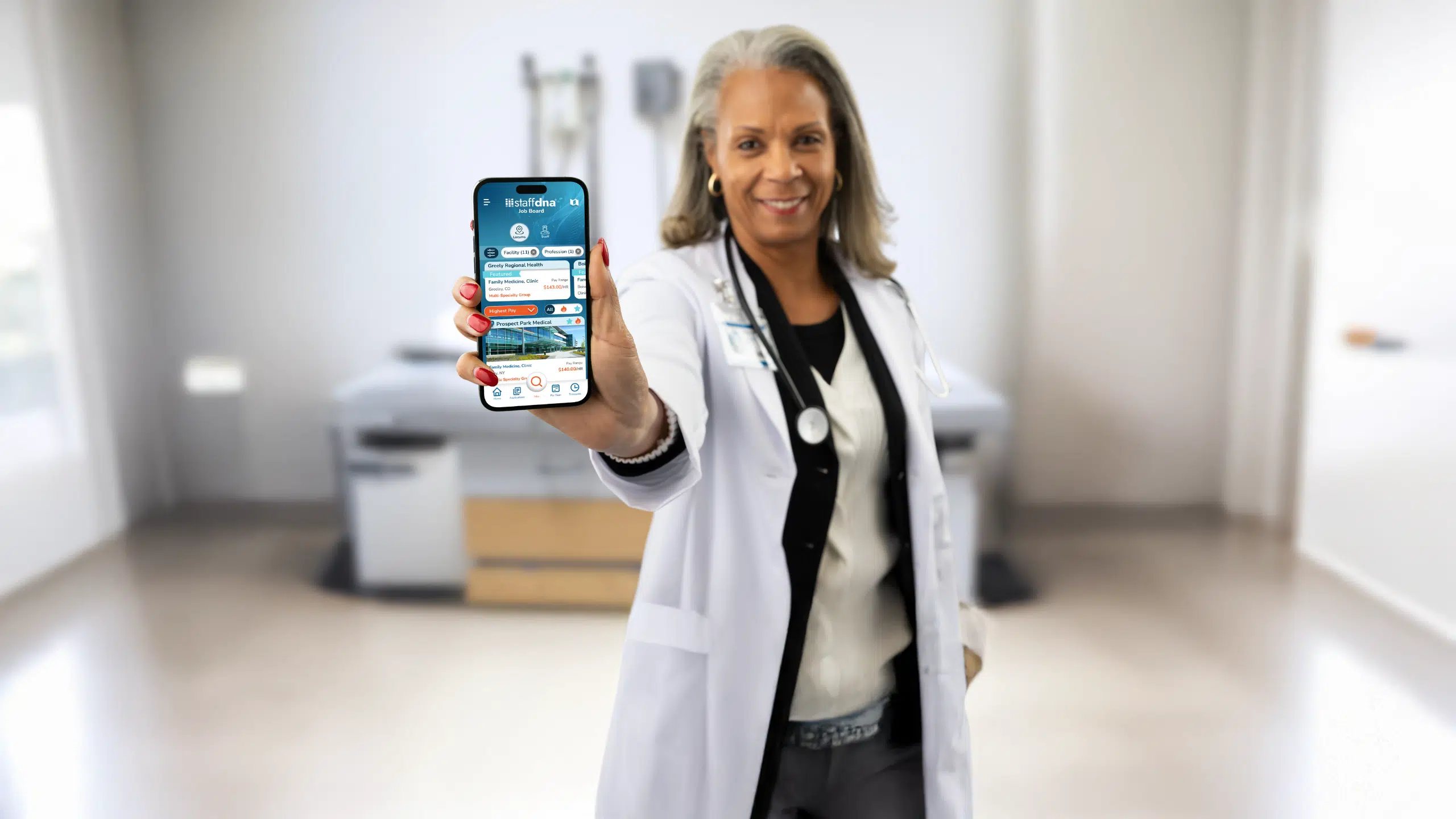 Finding a Job You Love Has Never Been Easier 1 Nurse in medical room holding a phone showcasing staffdna mobile app.