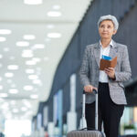 Elderly traveler with suitcase and passport.