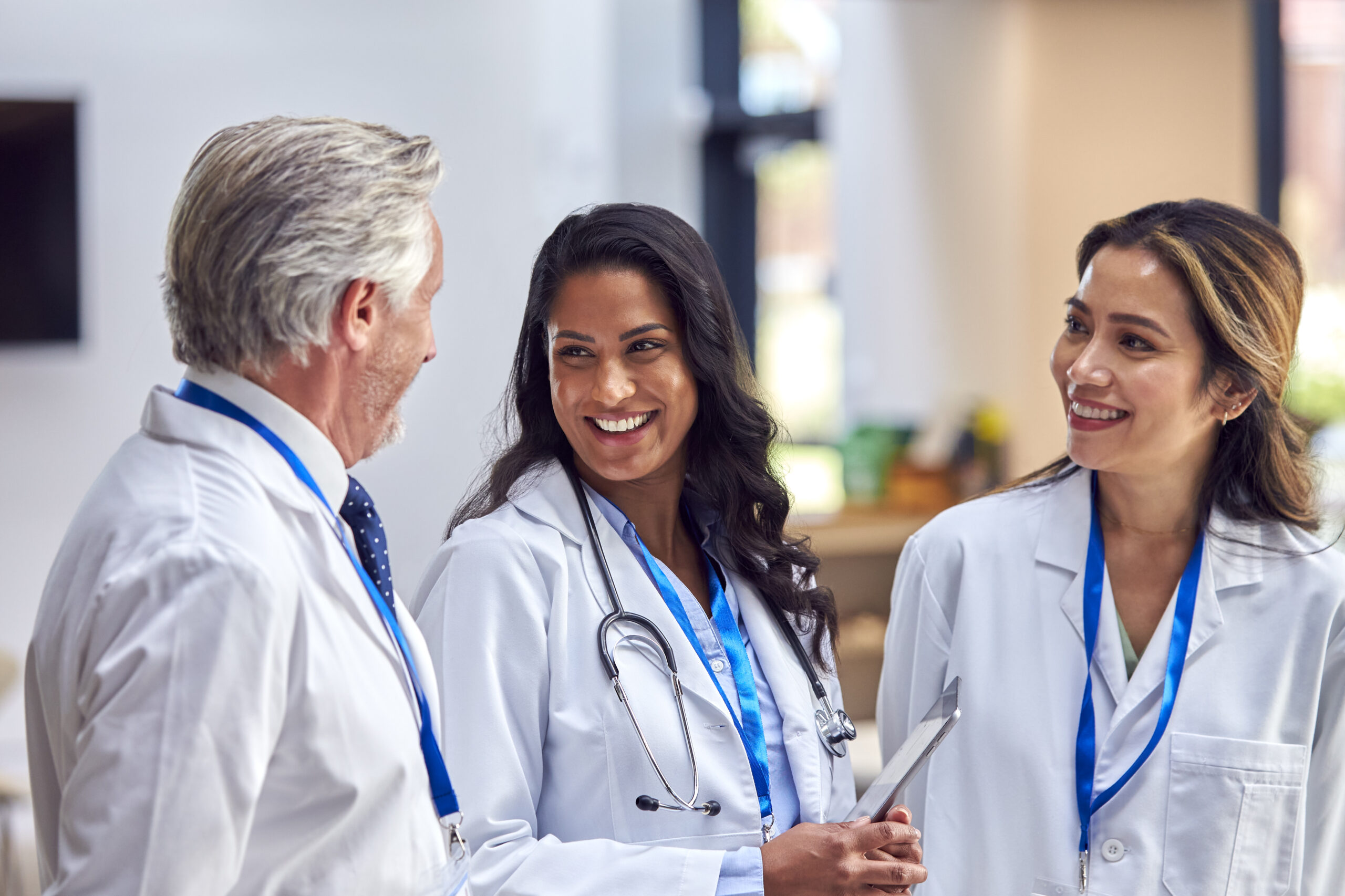 Three doctors discussing in hospital setting.
