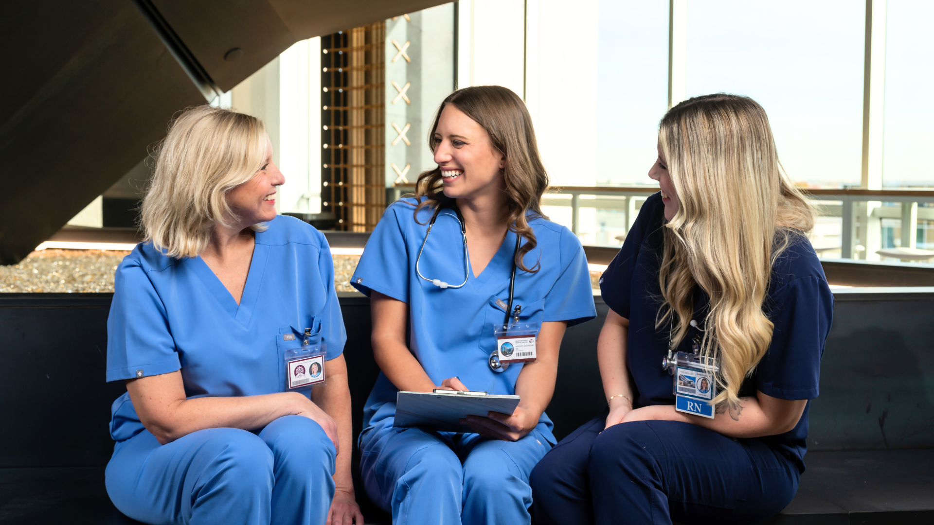 Three nurses discussing in hospital setting.